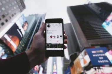 Main tenant smartphone avec Instagram ouvert, ville.