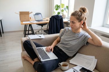 Femme travaillant sur ordinateur portable depuis son canapé