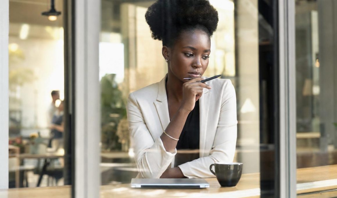 Femme réfléchissant dans un café avec tablette