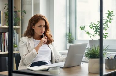 Femme réfléchissant devant ordinateur portable au bureau