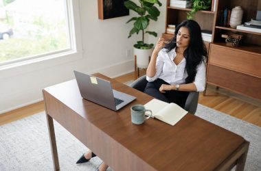 Femme réfléchissant devant un ordinateur portable au bureau