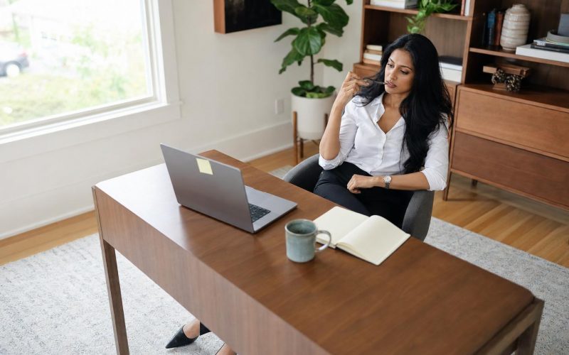 Femme réfléchissant devant un ordinateur portable au bureau